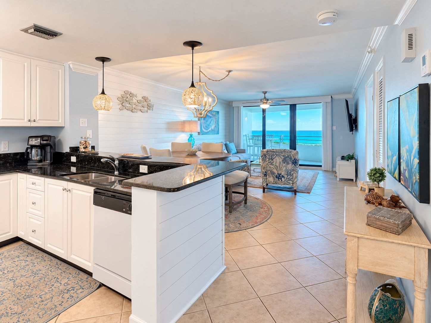 A modern kitchen with a central island, white cabinetry, and pendant lighting.