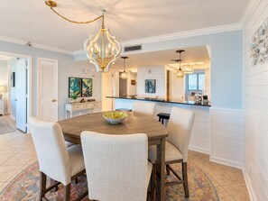 A dining area with a round table, chairs, a chandelier, and artwork on the walls.