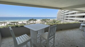 Ein Balkon mit Tisch und Stühlen mit Blick auf Strand und Meer.