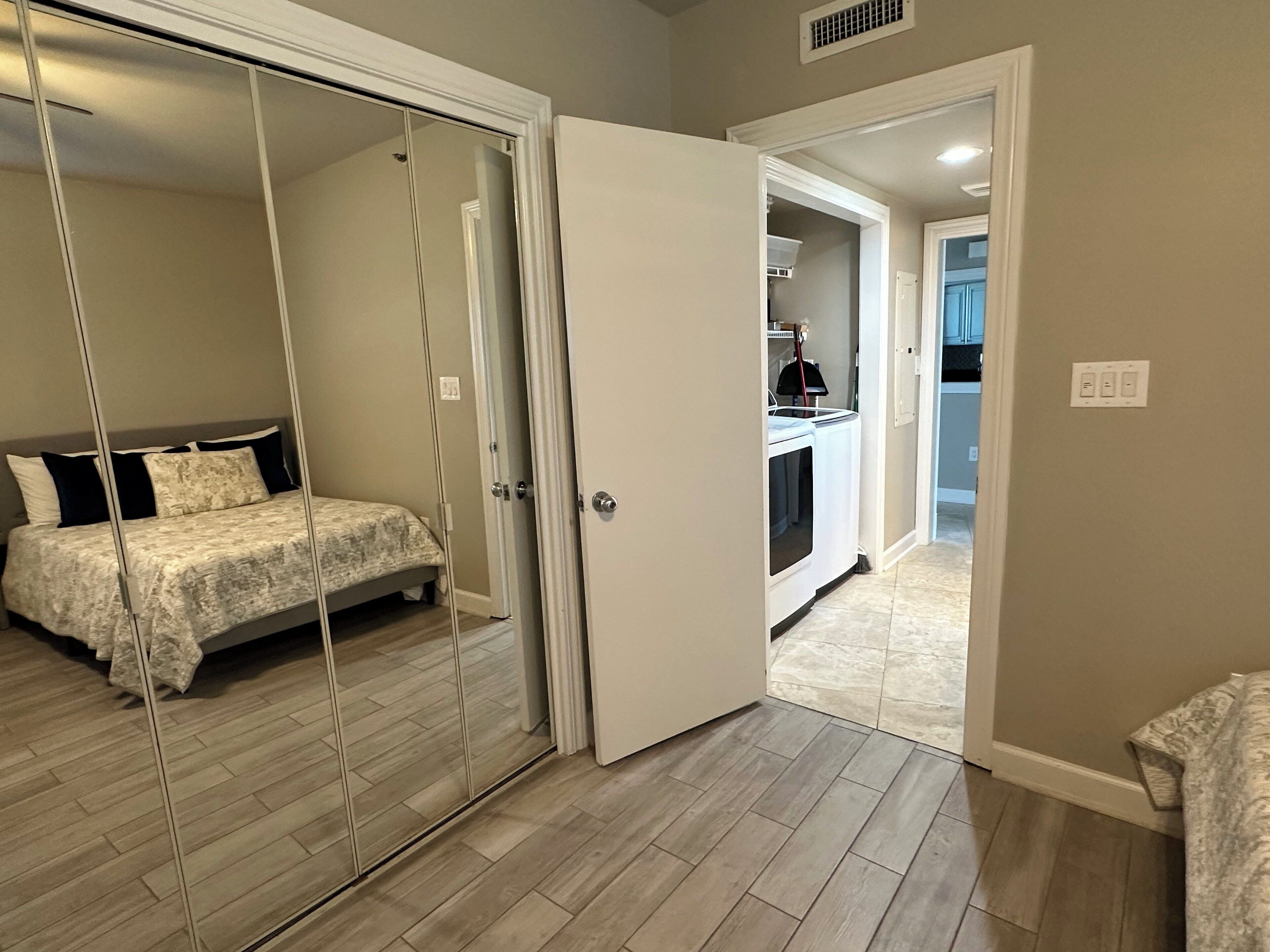 Un dormitorio con cama, vestidor y espacio para lavandería.