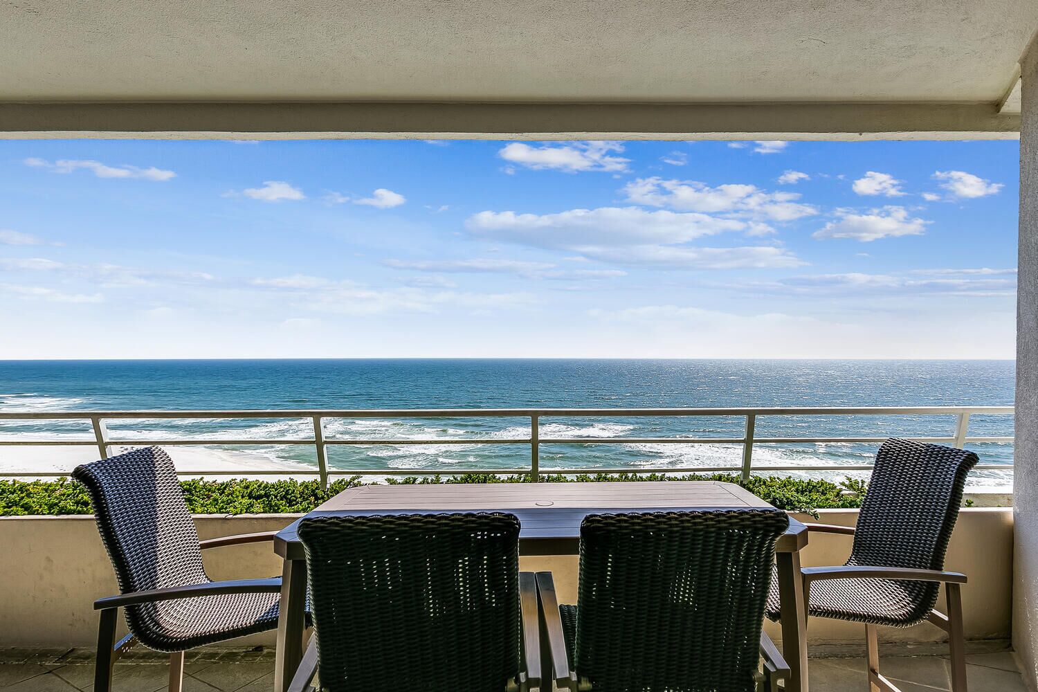 Un balcone con tavolo e sedie vista sull'oceano.