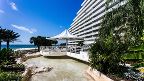 Un complexe hôtelier doté d’une piscine, de palmiers et offrant une vue sur l’océan.