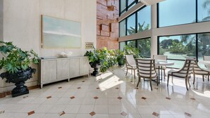 Un hall d’entrée spacieux avec un sol en marbre, un comptoir d’accueil et un espace détente comprenant des chaises et des tables.
