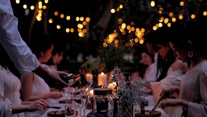 Una mesa de comedor dispuesta con velas, copas y un centro de mesa.