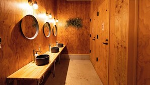 Un baño de madera con varios lavamanos, espejos y una planta.