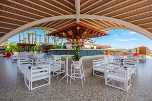 An outdoor dining area with white tables and chairs, a bar, and a view of palm trees and a pool. - Siu Collection Ultra All Inclusive (Kemer)