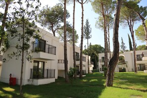 A residential building with multiple balconies, surrounded by tall trees and a well-maintained lawn. - Siu Collection Ultra All Inclusive (Kemer)
