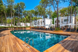 A swimming pool with wooden deck and lounge chairs, surrounded by white buildings and trees. - Siu Collection Ultra All Inclusive (Kemer)