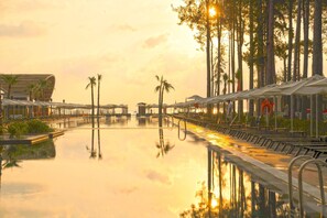 A pool area with lounge chairs and umbrellas, surrounded by palm trees and modern architecture. - Siu Collection Ultra All Inclusive (Kemer)