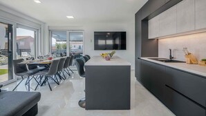 Una cocina moderna con una isla central, un comedor con sillas y un amplio ventanal con vistas al exterior.