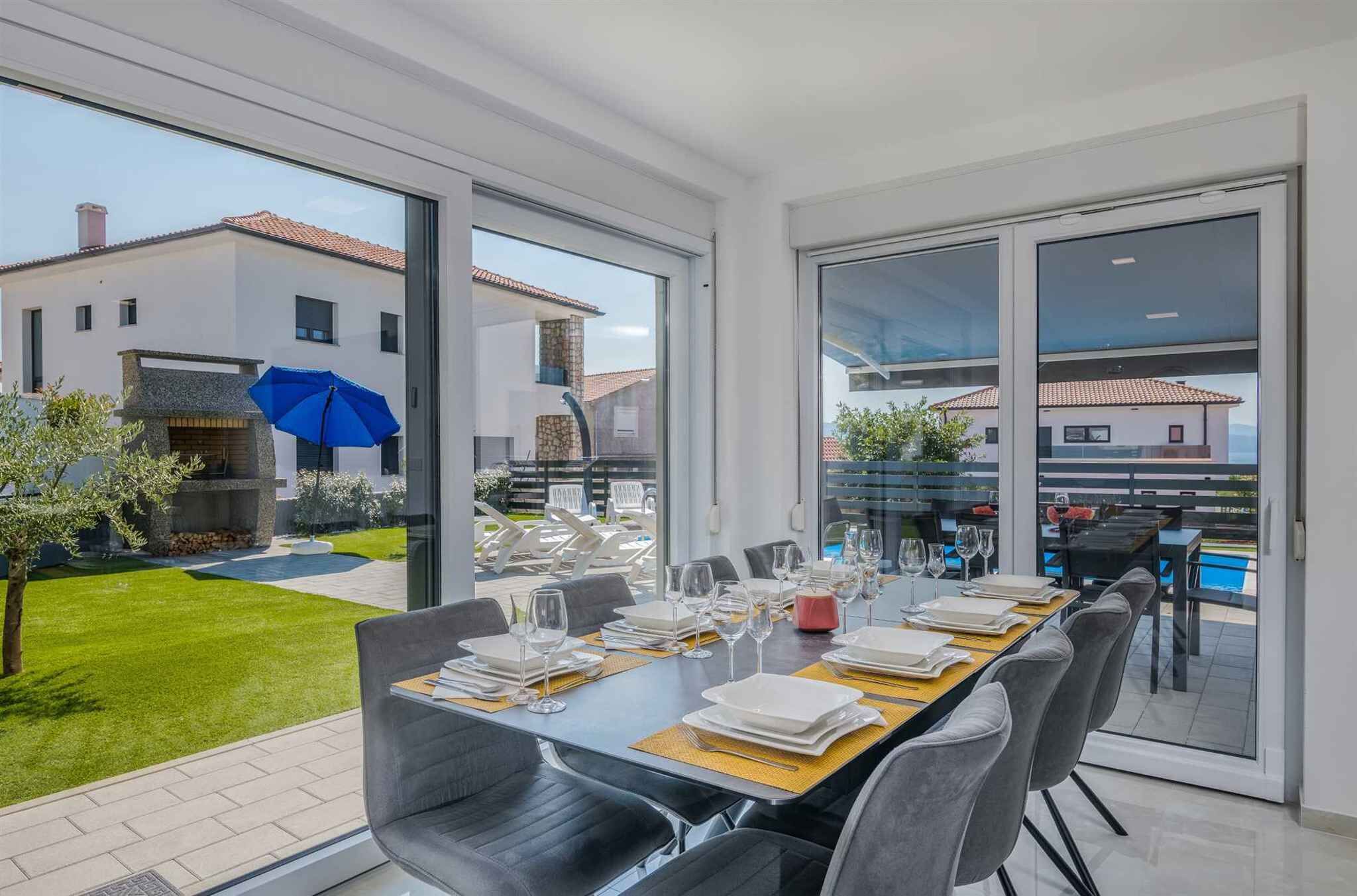 Comedor con una mesa para seis, ventanas amplias y vista a una zona residencial.