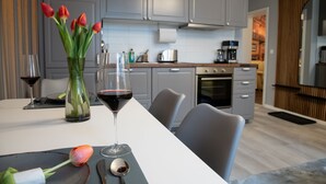 A modern kitchen with grey cabinets, a dining table with a vase of tulips, and a glass of red wine.