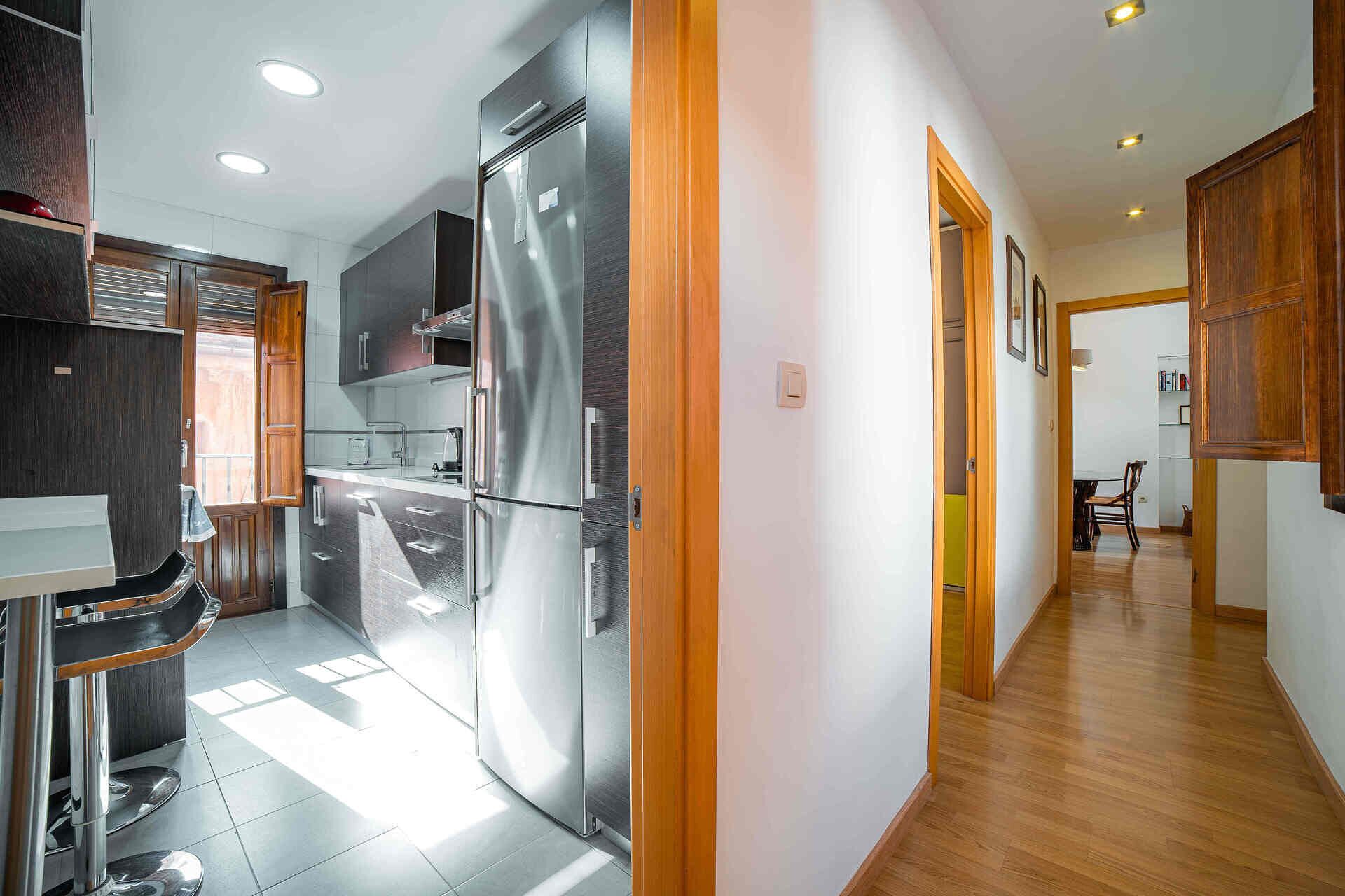 Una cocina moderna con un refrigerador de acero inoxidable, armarios de madera y un comedor con mesa y sillas.