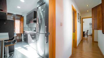 Una cocina moderna con un refrigerador de acero inoxidable, armarios de madera y un comedor con mesa y sillas.