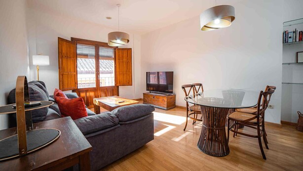Ett modernt vardagsrum med en soffa, ett soffbord, en tv och en matplats med stolar och ett bord i glas.
