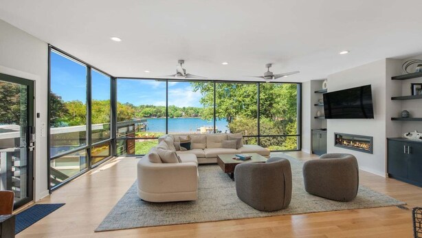 A modern living room with a large window, a fireplace, and a flat-screen TV. - Blue Haven w/Game Room, Hot Tub & Optional Boat Rental (Mooresville)