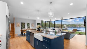 A modern kitchen with a large island, wooden flooring, and a view of a lake. - Blue Haven w/Game Room, Hot Tub & Optional Boat Rental (Mooresville)