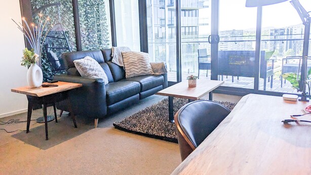 Een moderne woonkamer met een leren bank, een houten salontafel en een groot raam met uitzicht op de stad.