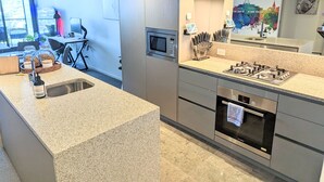 Een moderne keuken met granieten werkbladen, roestvrijstalen apparatuur en uitzicht op de omgeving.