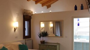 Un dormitorio con cama, lámparas de noche, cómoda, espejo y planta en maceta.