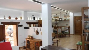 Una cocina amplia con electrodomésticos modernos, un comedor con mobiliario de madera y un espacio exterior visible a través de una puerta abierta.