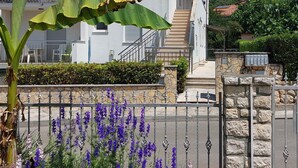 A two-story house with a balcony, a stone wall, and a gate.