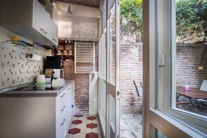 A kitchen with a brick wall, a window, and a view of the outside.