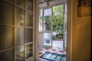 A doorway leading to a covered outdoor area with a glass door, a tiled floor, and a wall-mounted light switch.