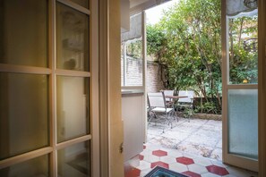 A doorway leading to an outdoor patio with a table and chairs.