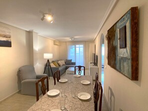 Relax in this stylish living room with a large sofa, armchair, and dining table for four.