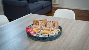 Una mesa de comedor con una bandeja de pan, mantequilla y salsas.