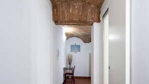 Un pasillo con techo de ladrillo, paredes blancas y baldosas de barro cocido.