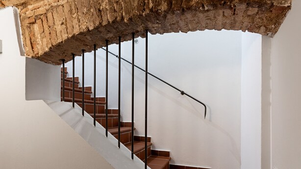 Una escalera con un arco de ladrillo y barandillas de metal.