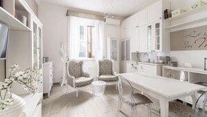 Une cuisine moderne avec des meubles blancs, une table à manger et deux chaises.