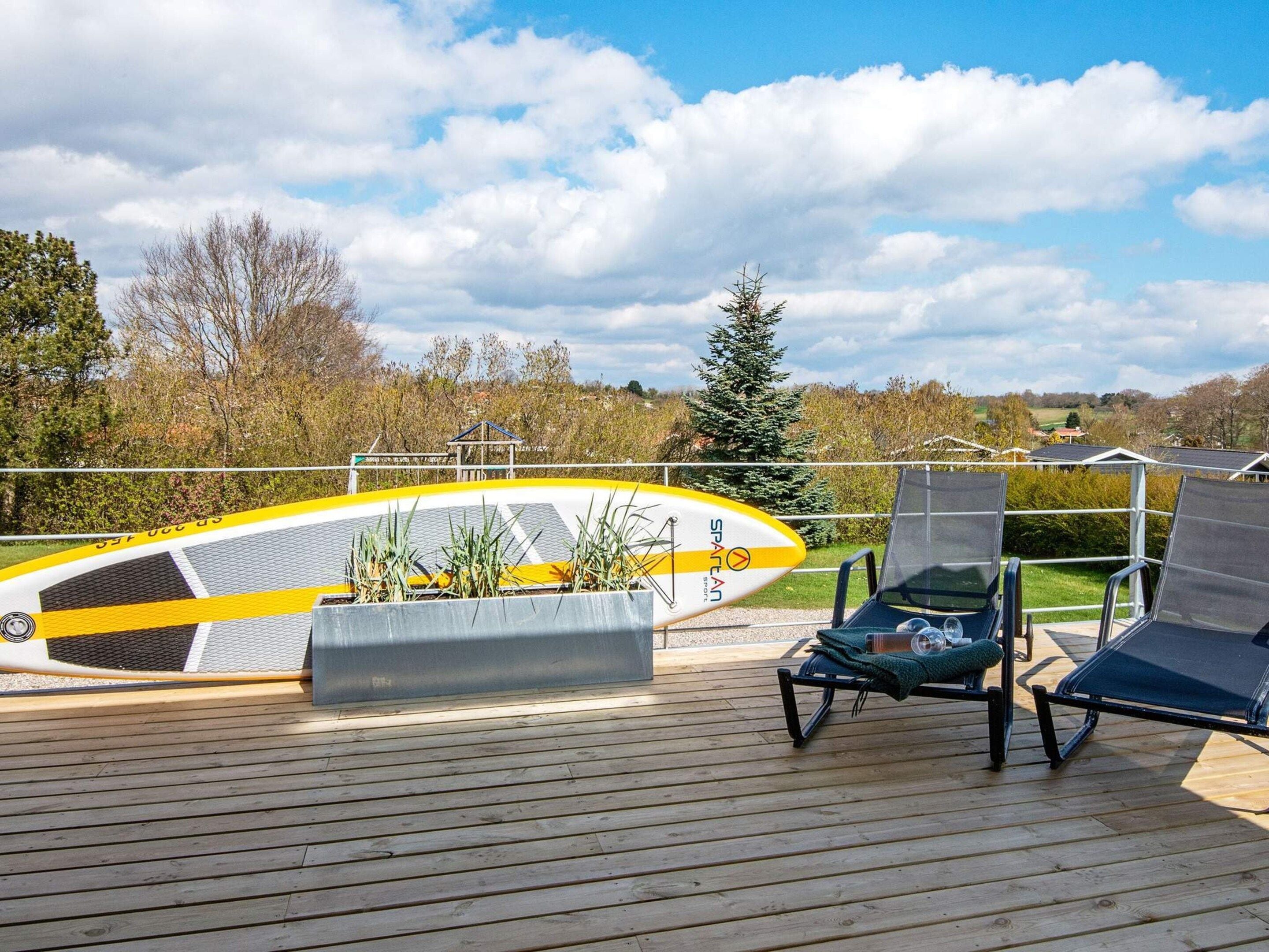 A wooden deck with a kayak and lounge chairs.