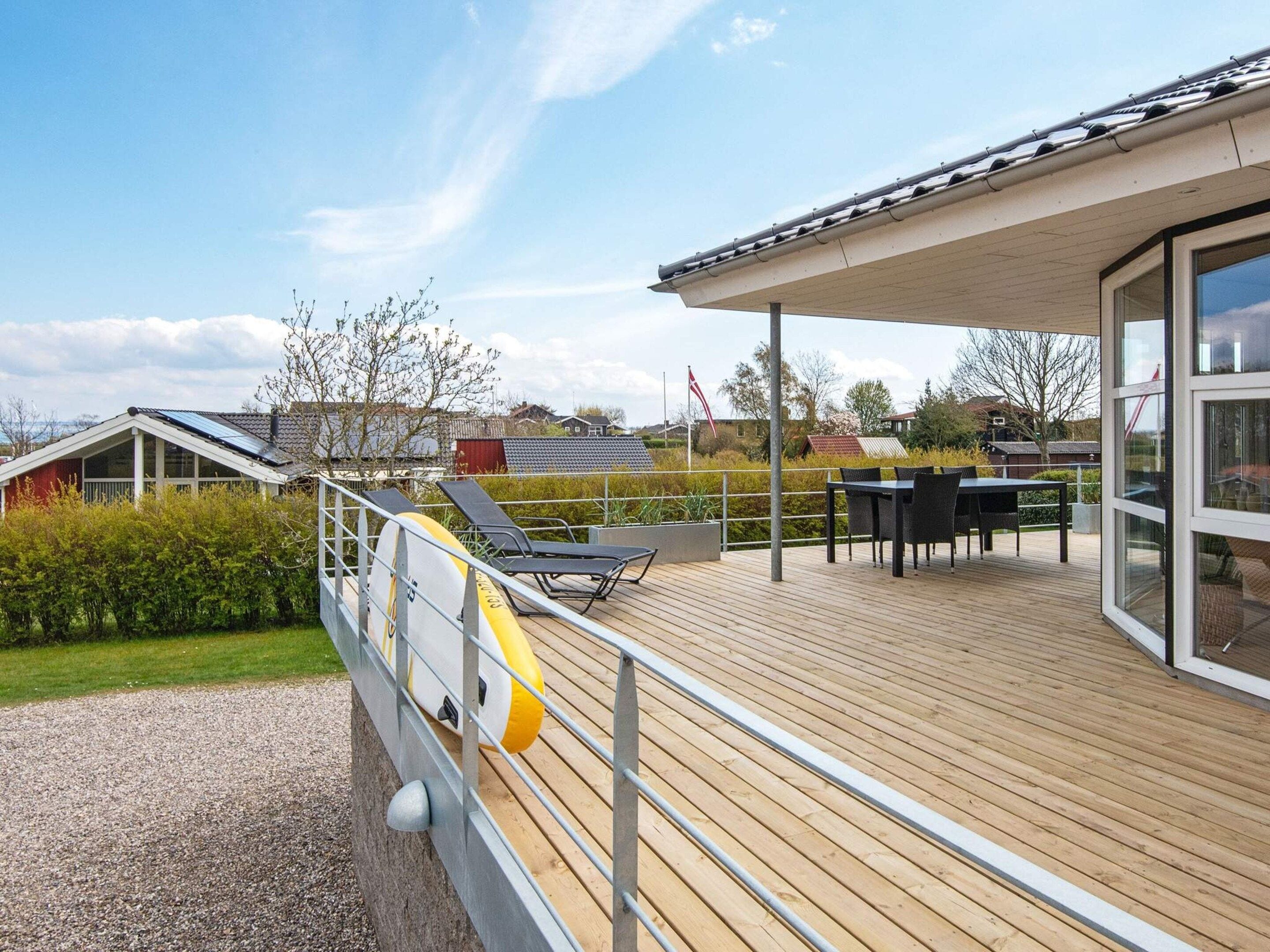 A wooden deck with outdoor furniture, a covered area with a table and chairs, and a view of the surrounding landscape.