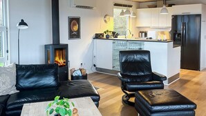 Un salon moderne avec un canapé en cuir noir, une table basse agrémentée d’objets décoratifs et une cheminée.