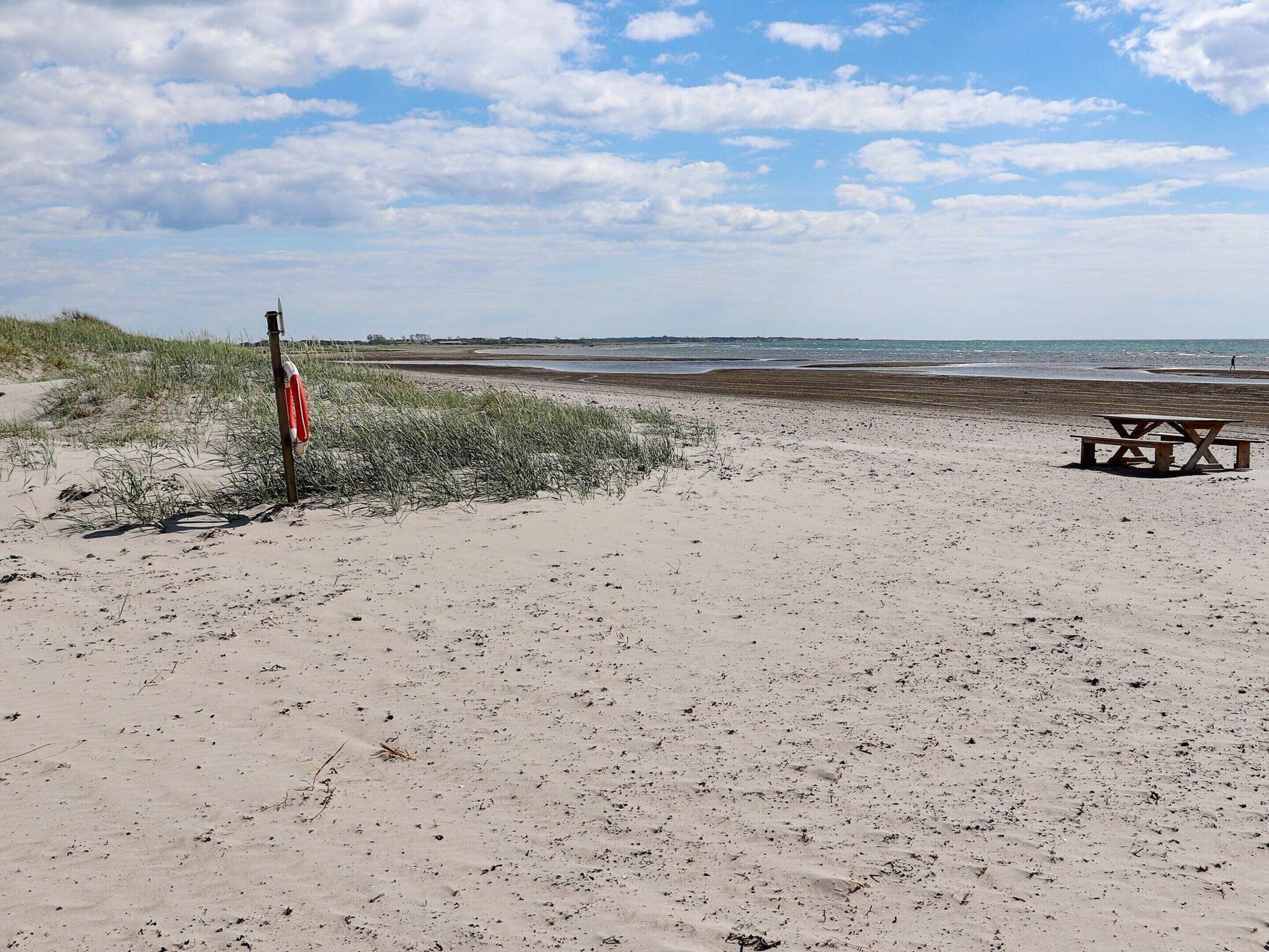 A beach with a lifeguard stand and a picnic table.