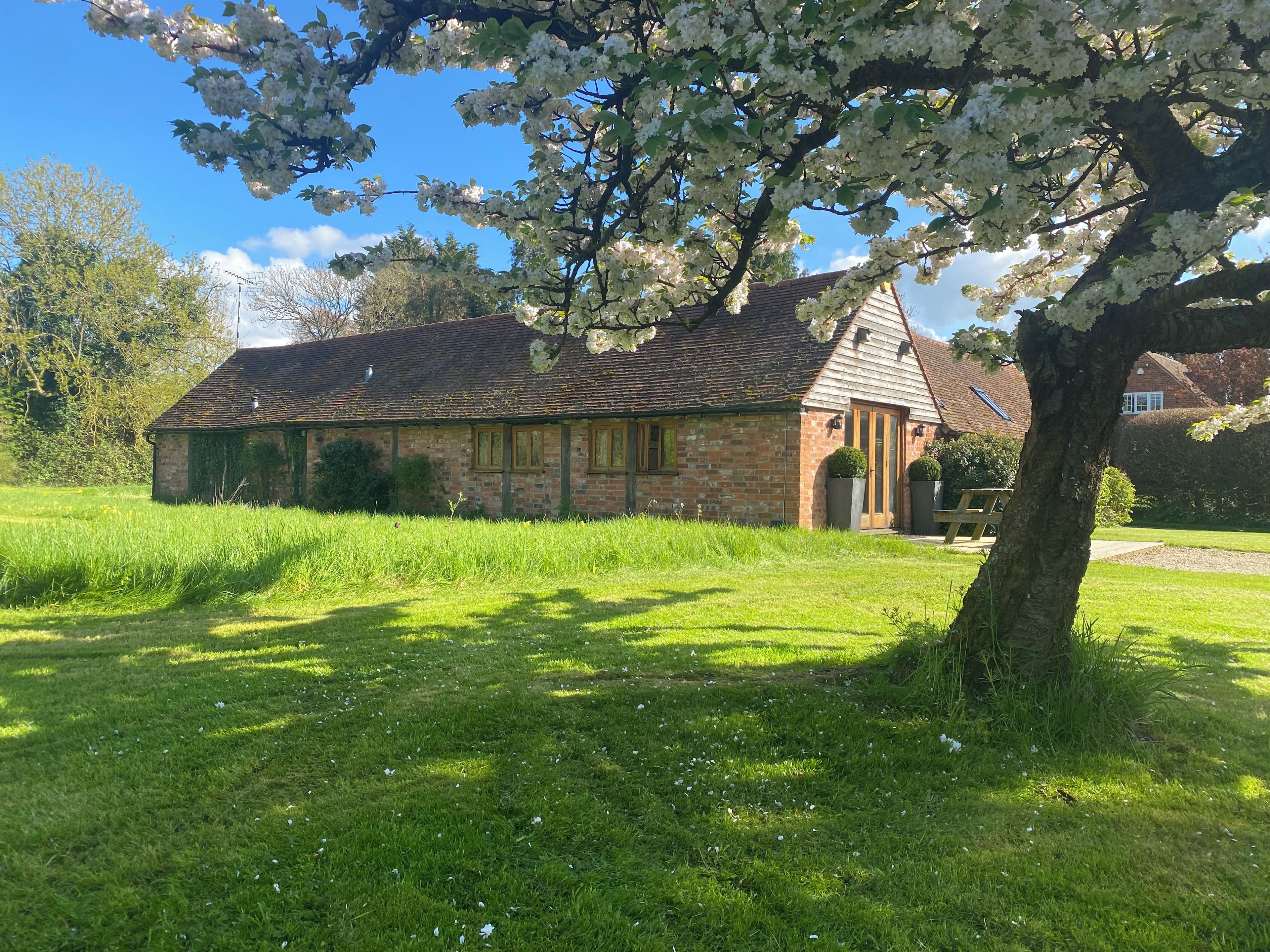 A stone building with a pitched roof, surrounded by a grassy field and trees.