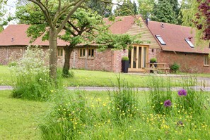 A brick building with a red-tiled roof, a wooden door, and a bench outside.