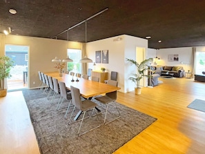 A modern living space with a dining area, a sofa set, and a large window. - 14 Person Holiday Home in Vaeggerlose (Vaeggerlose)