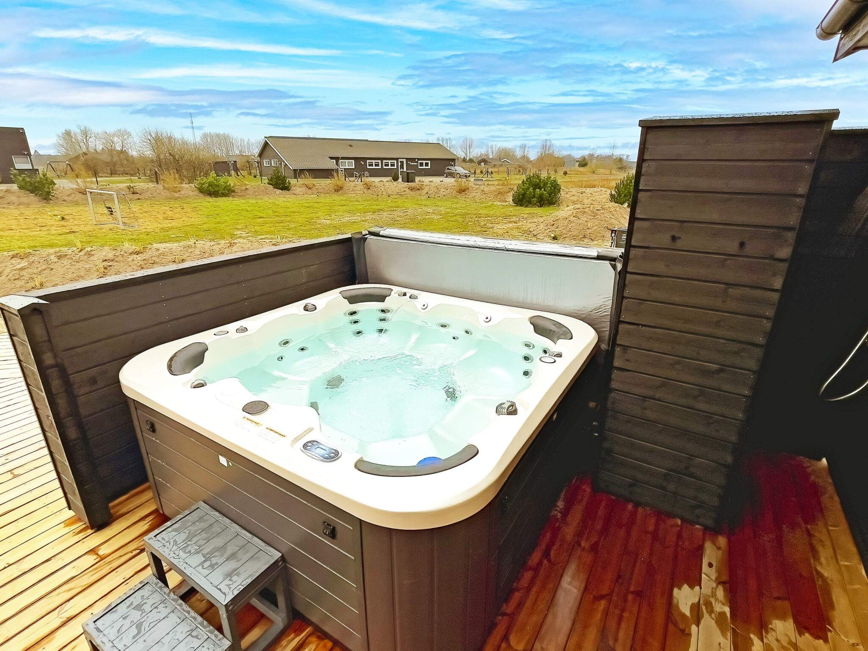 A hot tub on an outdoor deck with a view of a residential area.