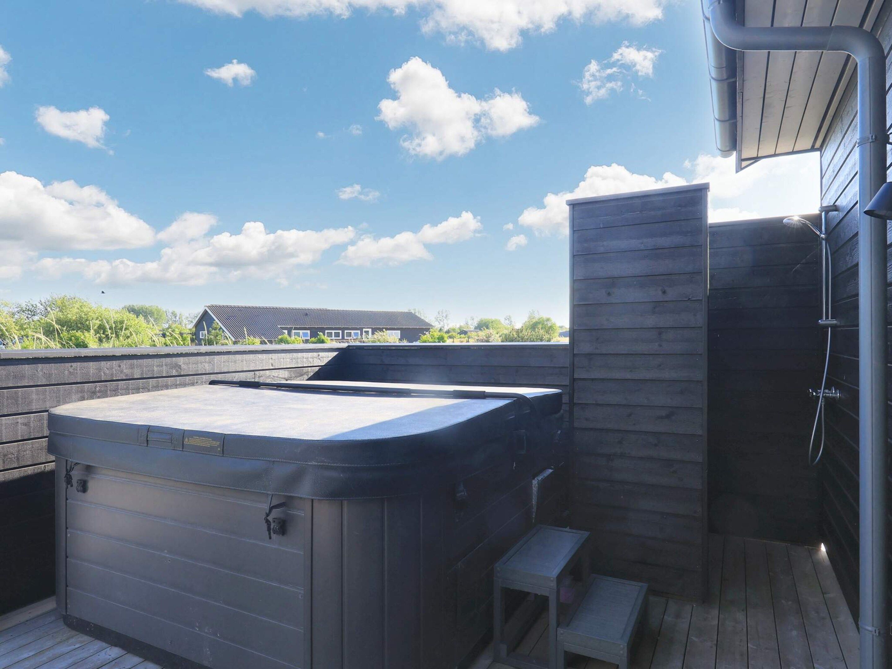 A hot tub on a wooden deck with a view of a building in the background.