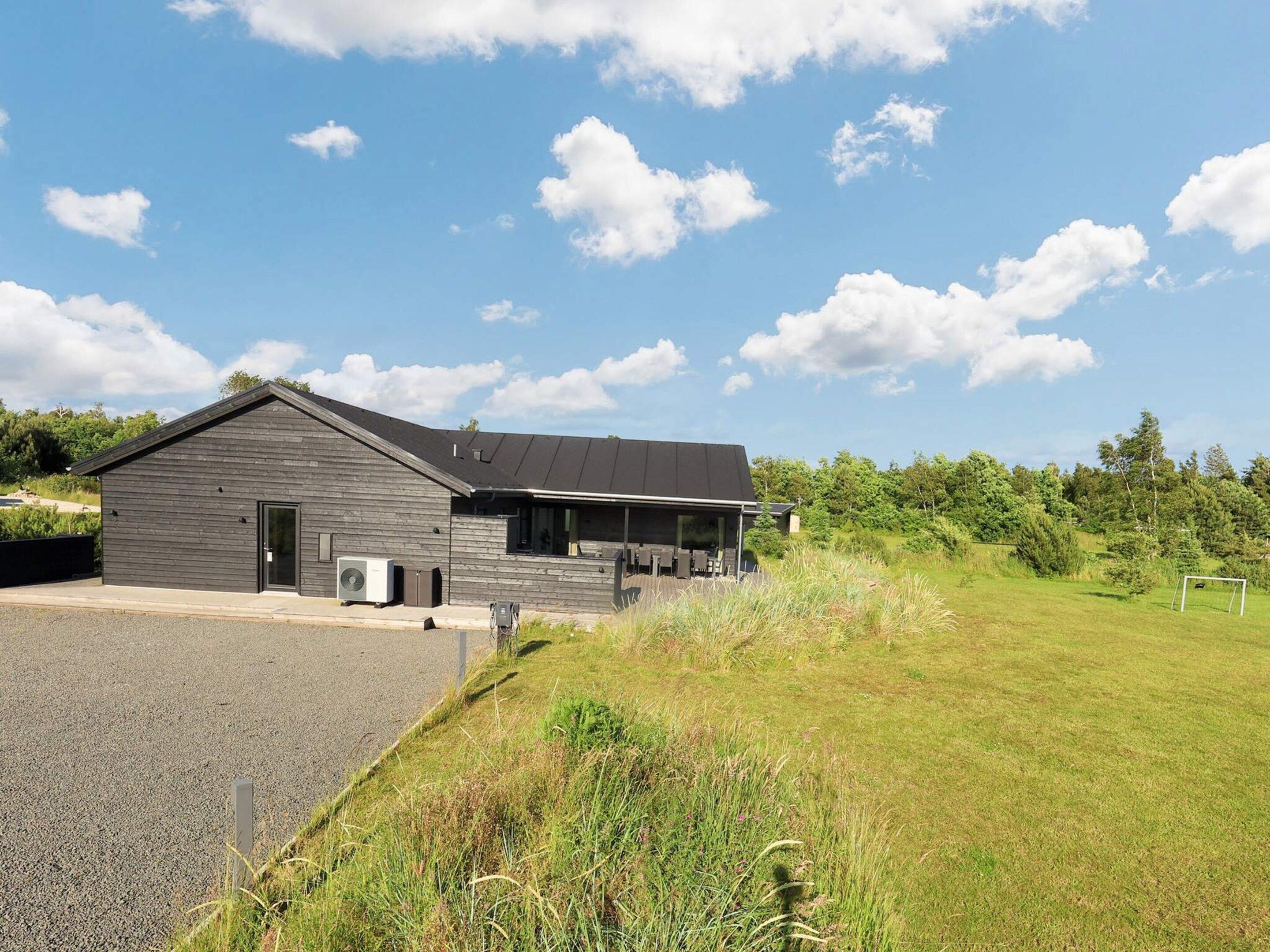 Een modern gebouw met een schuin dak, een overdekt terras en een verharde oprit.