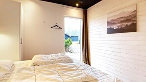 A bedroom with a bed, a door, a window, and a wall-mounted picture. - 14 Person Holiday Home in Vaeggerlose (Vaeggerlose)