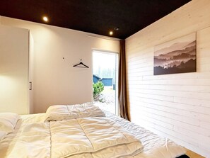 A bedroom with a bed, a door, a window, and a wall-mounted picture. - 14 Person Holiday Home in Vaeggerlose (Vaeggerlose)