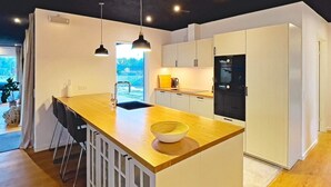 A modern kitchen with a central island, pendant lights, and a view of the outdoors. - 14 Person Holiday Home in Vaeggerlose (Vaeggerlose)
