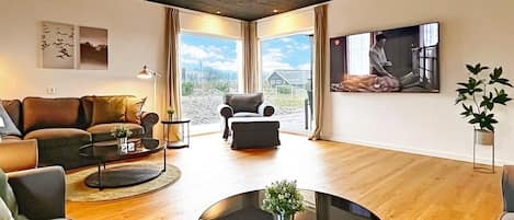 A modern living room with a sofa, armchairs, a coffee table, and a TV.