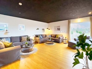 A modern living room with a sofa set, coffee table, and a large window offering a view. - 14 Person Holiday Home in Vaeggerlose (Vaeggerlose)