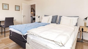 A neatly arranged bedroom with a bed, bedside table, lamp, and a chair. - 3 Person Holiday Home in Aeroskobing (Aeroskobing)